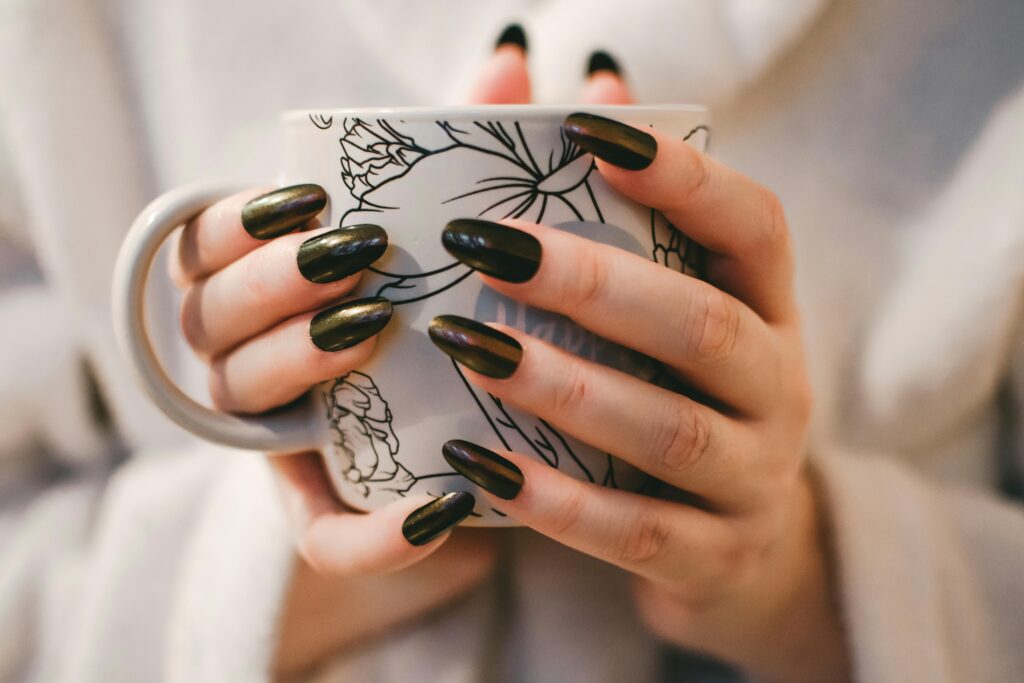 A close-up of manicured hands holding a decorative mug, perfect for lifestyle and coffee themes.